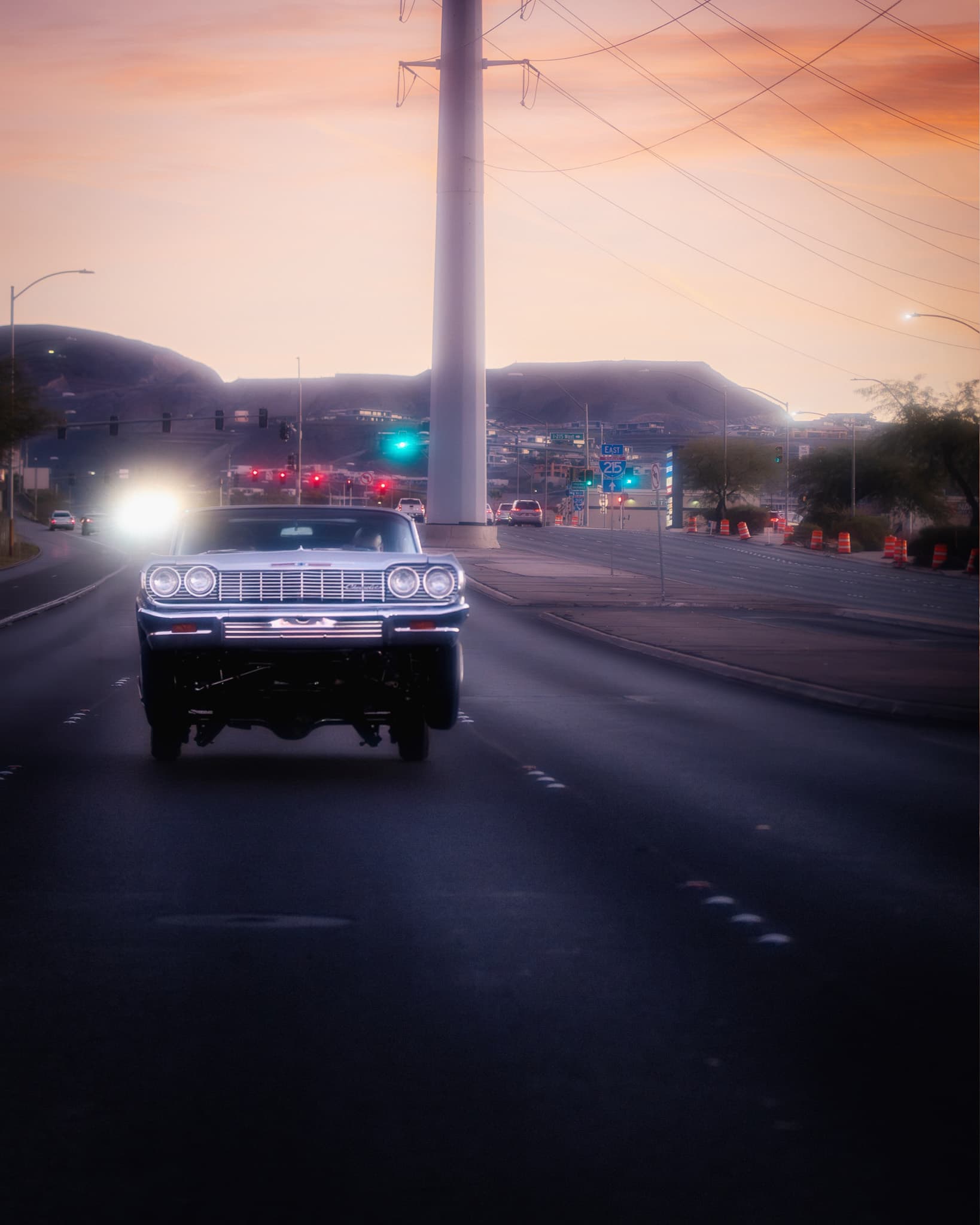 Lowrider Impala hitting 3-wheel on a Las Vegas highway at sunset with desert mountains