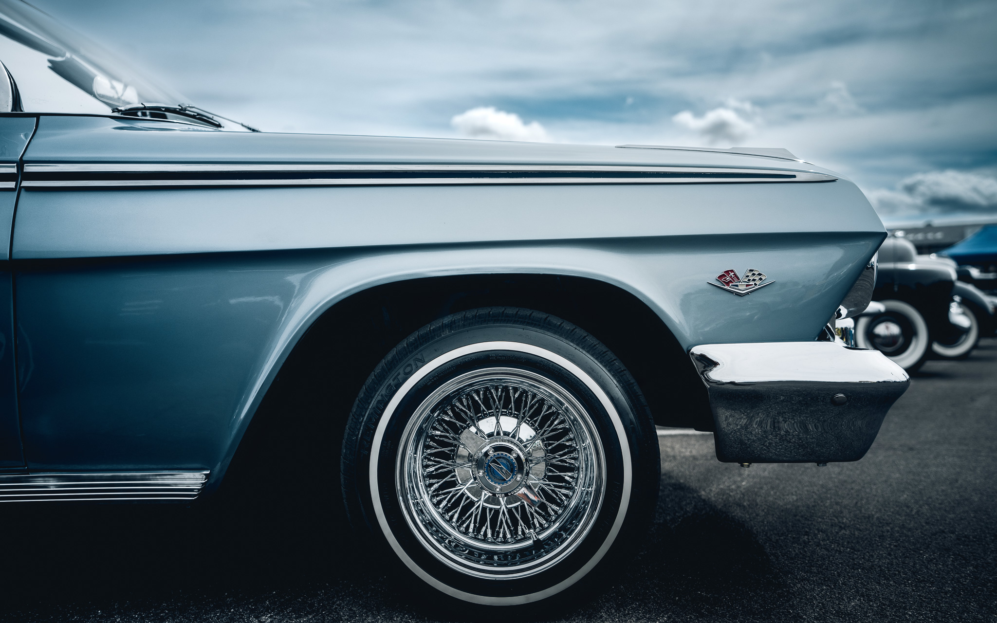 Professional lowrider chrome wire wheel detail photography against dramatic cloudy sky - mkegzy Photography Las Vegas